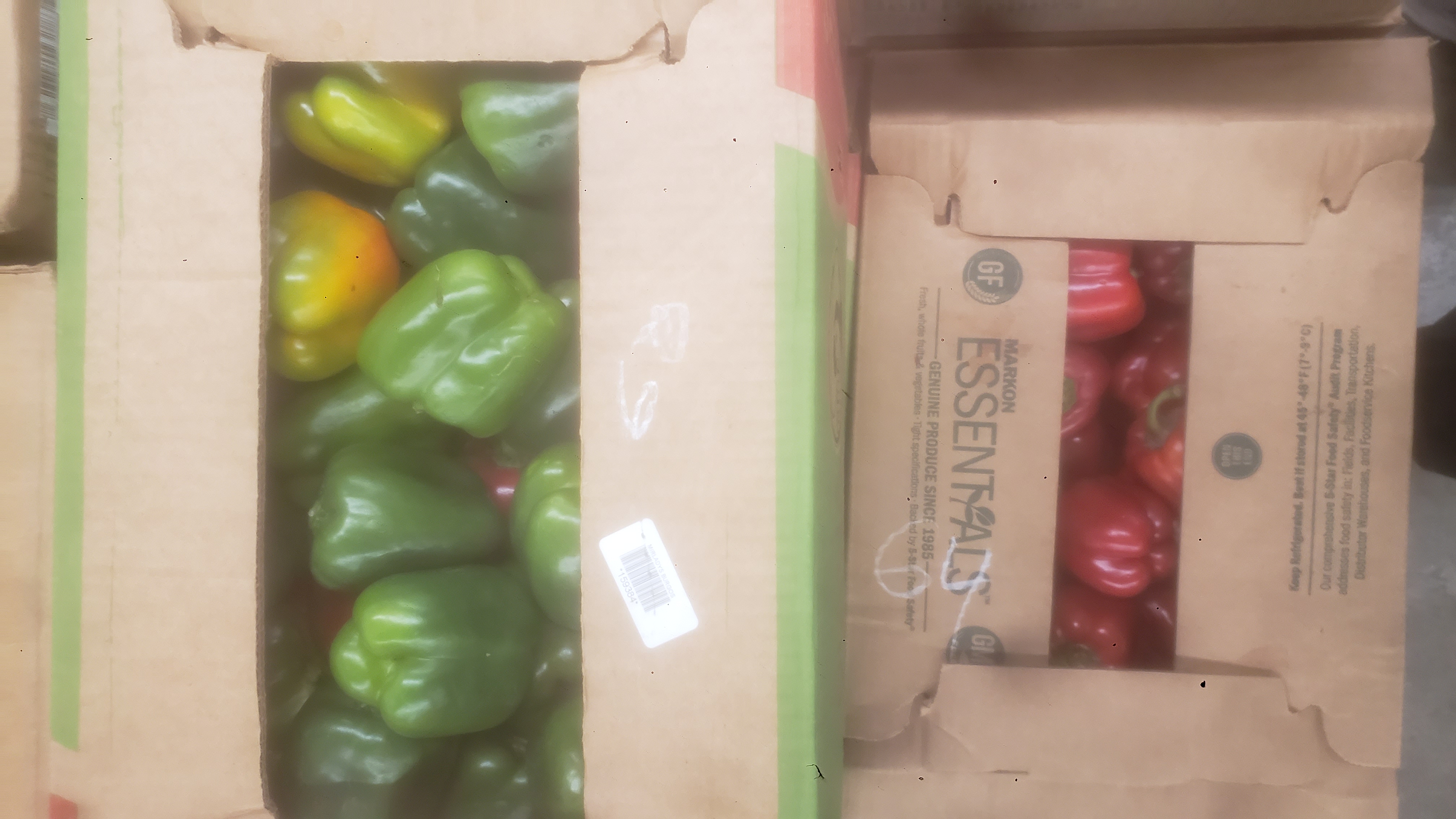 One box of green bell peppers and another of red bell peppers.